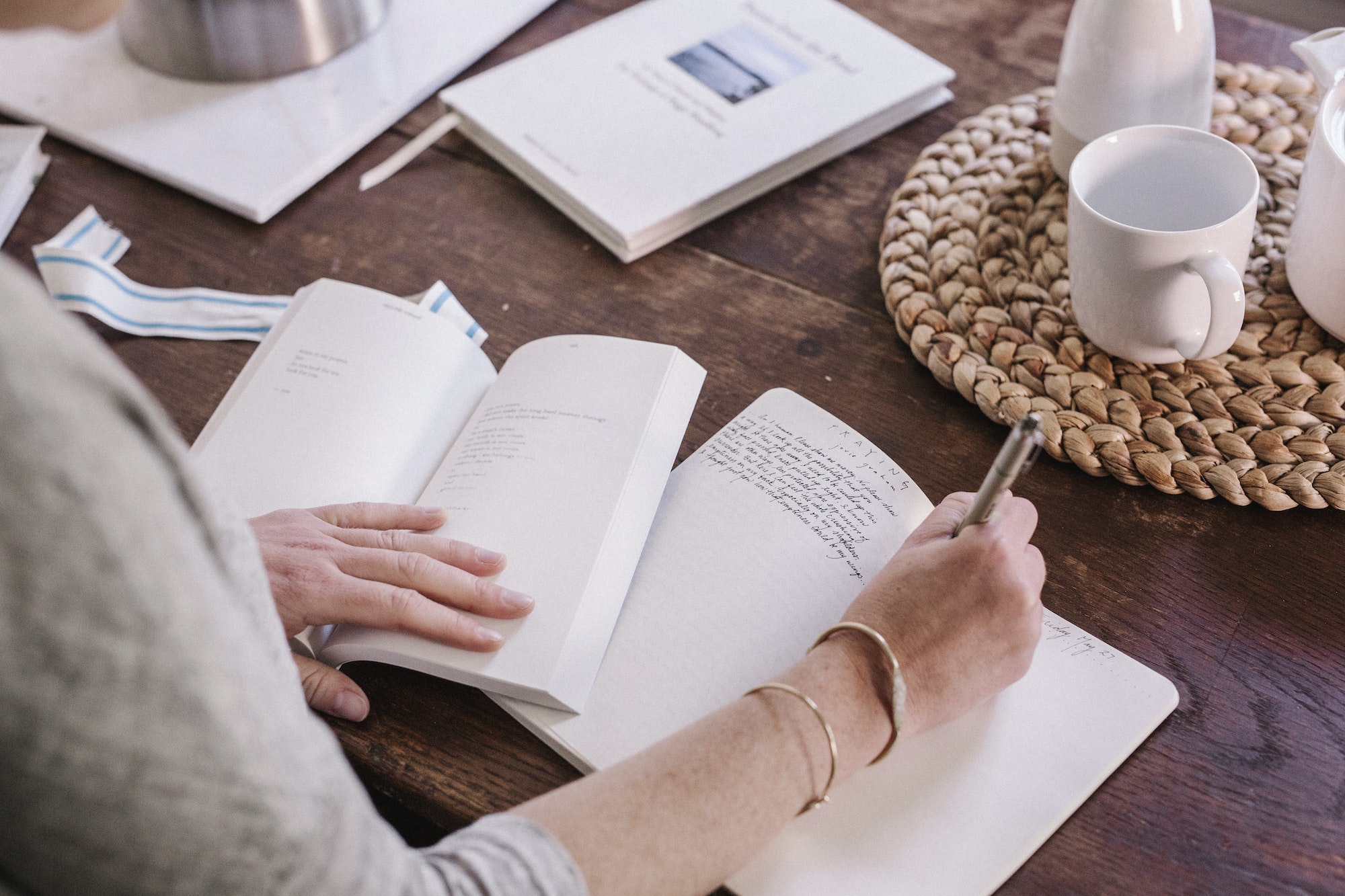 Woman sitting at a table in her apartment, writing in a diary, morning routine.